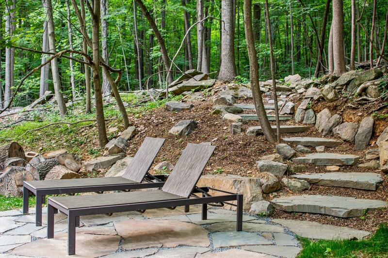 Across the lawn from the house, a new patio was created to serve as a landing point to a series of new steps meandering up the hillside to an enclave of hammocks in the woods.